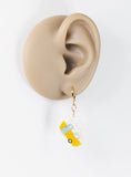 Earring with a skateboard design hanging from an ear on a white background