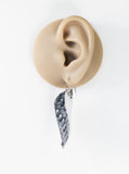Earring displayed on a mannequin ear with a white background