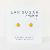 Yellow ear sugar earrings on a white background with text indicating hypoallergenic and surgical steel material.