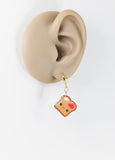 Earring shaped like a piece of toast with a heart on a white background